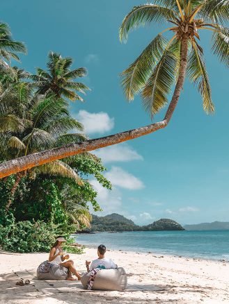 COMO Laucala Island Travel Diary by Jyo Shankar - couple picnicing on a beach under a palm tree