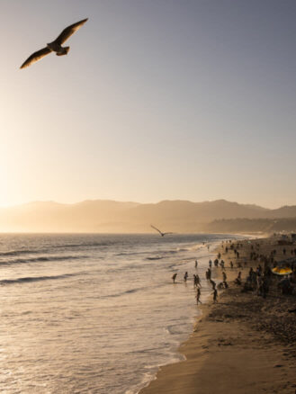 Best Places to Travel in 2026 featuring Route 66 and Santa Monica, Courtesy Visit California and Max Whittaker | a group of people on the beach in Santa Monica