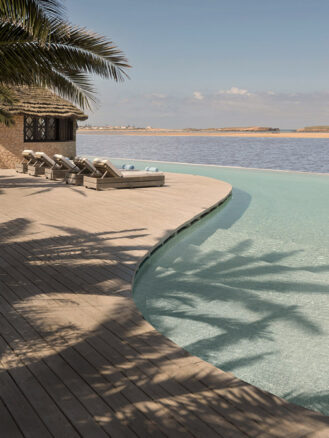 Family Trip to Morocco Travel Diary by Anna Cort | a pool with lounge chairs and a hut on the side at La Sultana Oualidia, Morocco