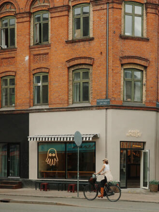 Copenhagen to Berlin Travel Diary | A woman riding a bike past Hart Bageri in Copenhagen