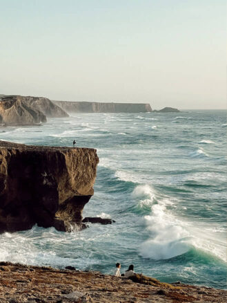 Portugal and Spain Travel Diary Itinerary by Christine Flynn | a person standing on a cliff overlooking the ocean in The Algarve, Portugal