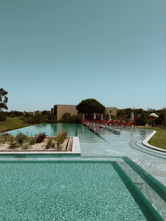 Portugal and Spain Travel Diary Itinerary by Christine Flynn | a pool with lounge chairs and grass at Praia do Canal in The Algarve, Portugal