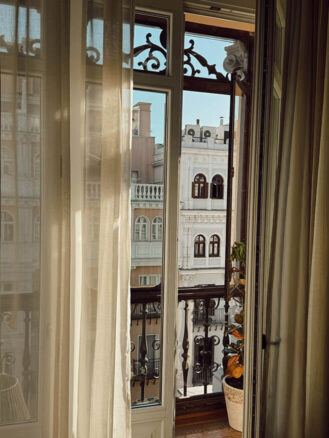 Portugal and Spain Travel Diary Itinerary by Christine Flynn | a window with curtains and a balcony overlooking the city at Nômade Temple Madrid, Spain