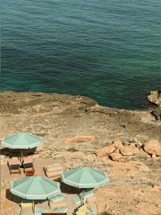 Portugal and Spain Travel Diary Itinerary by Christine Flynn | a group of chairs and umbrellas on a rocky beach at Six Senses Ibiza in Spain