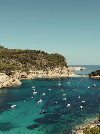 Portugal and Spain Travel Diary Itinerary by Christine Flynn | boats in a body of water in Northern Ibiza with boats in it as seen from Cala San Miguel Resort in Spain