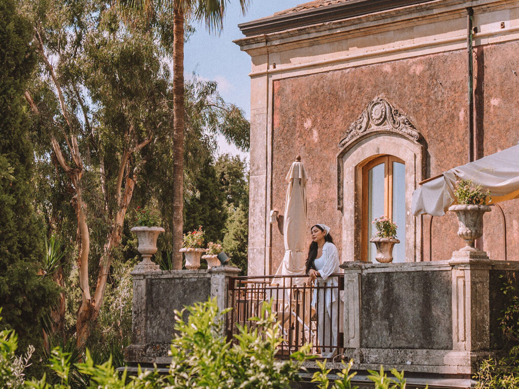 Where to stay in Sicily travel diary - Cherrie Lynn looking out at the scenery from a patio at Monaci delle Terre Nere Etna Wine Resort.