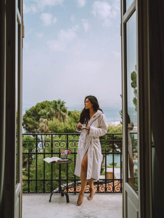 Where to stay in Sicily travel diary - Cherrie Lynn drinking coffee on a guestroom patio at Villa Igiea