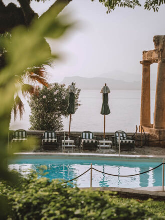 Where to stay in Sicily travel diary - Villa Igiea pool with striped loungers beside it and the ocean beyond