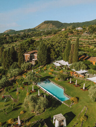 Where to stay in Sicily travel diary - aerial view of Monaci delle Terre Nere Etna Wine Resort, featuring the hotel pool and hotel behind it
