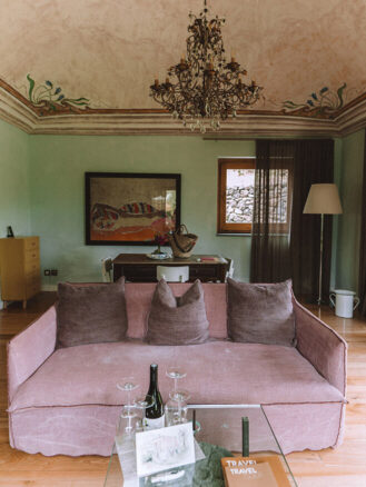 Where to stay in Sicily travel diary - pink couch in a green living room in a private villa at Monaci delle Terre Nere Etna Wine Resort
