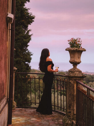Where to stay in Sicily travel diary - Cherrie Lynn looking out over the scenery from a patio at Monaci delle Terre Nere Etna Wine Resort